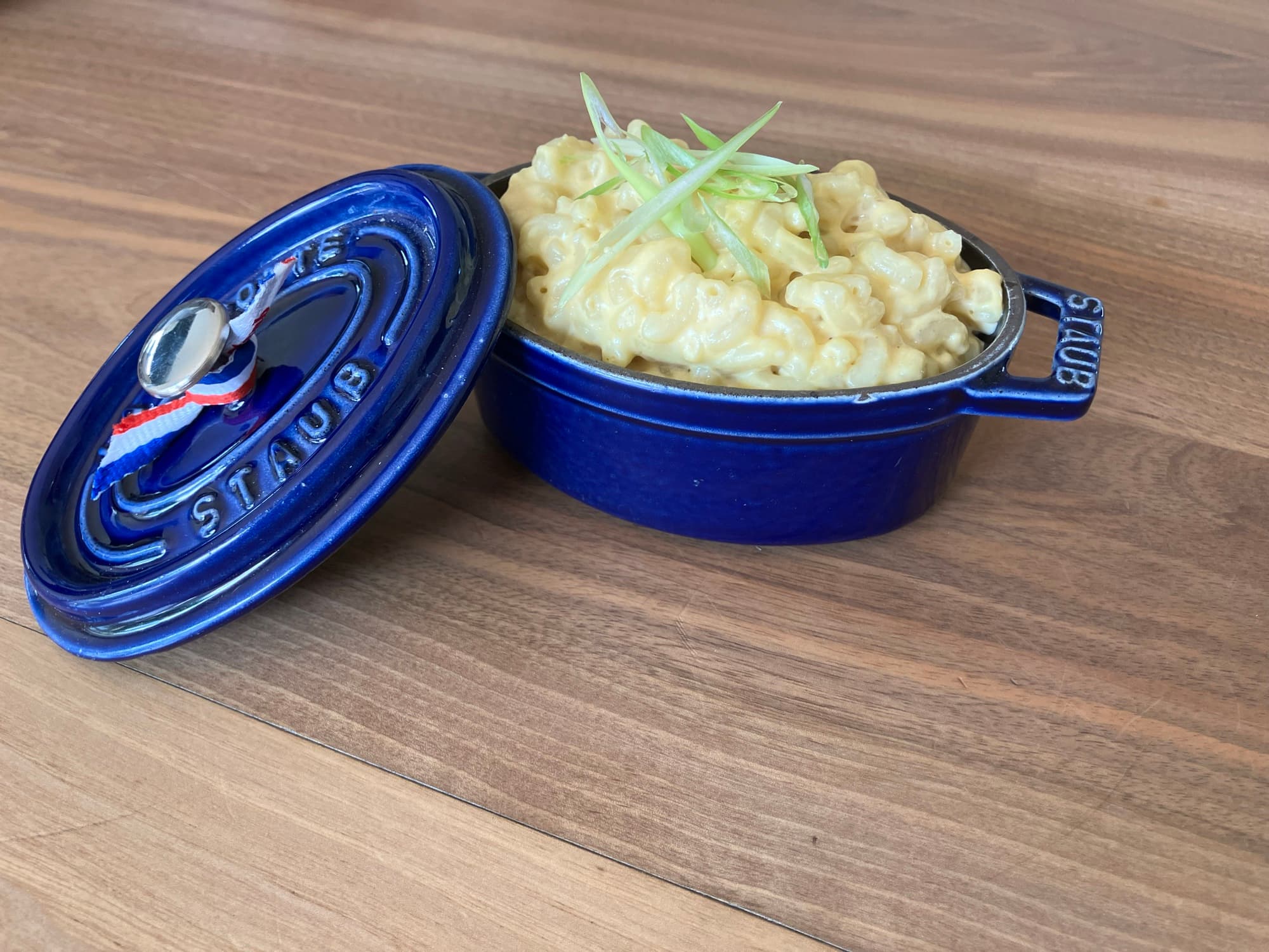 Gros plan du Truffle Mac & Cheese dans une cocotte Staub, garni de ciboule fraîche